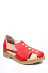 Zapato tipo sandalia plana de cuero liso en color rojo cereza con detalles en color crema. Presenta paneles laterales elásticos, suela dentada y diseño con aberturas.