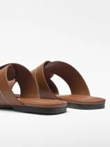 Sandalia plana color marrón con tiras de cuero entrelazadas y puntera cuadrada.