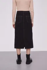 Falda midi de jean color negro, de tiro alto y corte recto. Presenta costuras a la vista en color ocre y cierre frontal con botón y cremallera.