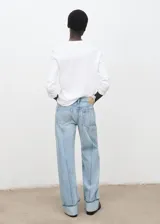 Jeans tiro medio color celeste, de diseño recto y largo, con bajo vuelto, trabillas, cierre de botón y cremallera, estilo cinco bolsillos y detalle de costuras verticales.