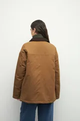 Campera color verde militar con cuello de pana marrón, bolsillos con solapa y botones metálicos. Interior forrado con tela satinada capitoneada.