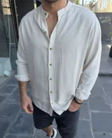 Camisa de lino color arena, de corte recto y manga larga, con cuello mao y abotonadura frontal.