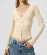 Cardigan de tricot acanalado color beige, de calce ajustado, con mangas largas y escote en V. Cuenta con cierre frontal con botones y detalles de encaje aplicado en el escote y el ruedo.