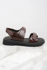Sandalias marrones de cuero con suela de goma negra y ajuste con velcro.