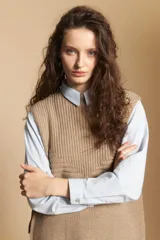 Chaleco de tejido de punto en color crema, con cuello alto y diseño acanalado. Presenta una silueta relajada con aberturas laterales.