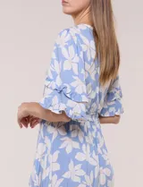 Vestido midi de calce holgado y caída fluida con escote en V cruzado, cintura elastizada fruncida y mangas cortas con volados superpuestos. Cuenta con un diseño estampado de flores grandes en tonos amarillo, blanco, azul marino y verde.