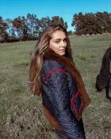 Campera acolchada de diseño artesanal, con detalles de piel sintética en cuello, puños y ruedo. Presenta costuras decorativas en crochet color rojo en los bolsillos y hombros, con cierre frontal.