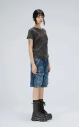 Bermuda de denim azul oscuro con lavado y efecto desgaste, corte oversize y estilo cargo con múltiples bolsillos con tapa en las piernas.