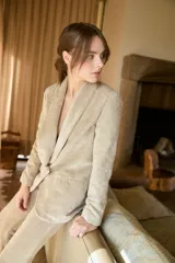 Blazer de terciopelo color beige, con solapas tipo chal, cierre frontal de un botón y bolsillos laterales con solapa.