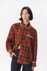 Camisa de corte holgado en color bordó con estampado de cuadros y monograma. Presenta cuello redondo con borde de puntilla, bolsillo frontal con detalle de puntilla, cierre frontal con botones y puños con terminación en puntilla.