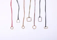 Set de seis collares con cordón de distintos colores y dijes geométricos de metal.