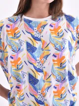 Remera de manga corta color beige con estampado de bananas en tonos amarillo, naranja y rosado.