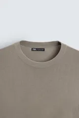 Jersey color crudo de tejido de punto, con cuello redondo y mangas largas. Corte amplio y terminaciones en rib.