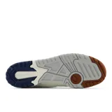 Championes New Balance 550 de cuero color crema con detalles en marrón y azul marino.