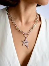 Collar de cadena de eslabones gruesos plateados con un dije central en forma de estrella decorado con pequeñas piedras brillantes.