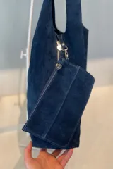 Bolso tipo hobo grande confeccionado en cuero vacuno color marrón, con costura central vertical y placa metálica con el logo de la marca Pecarí.