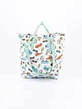 Mochila blanca con estampado de videojuegos, skateboards, lentes de sol y otros elementos. Tiene asas de mano y tiras para colgar en la espalda, ambas en color verde agua.