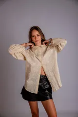 Camisa de manga larga con diseño abullonado, confeccionada en tela bordada con motivos florales. Presenta cierre frontal con botones y puños elásticos.