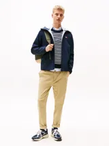 Campera cortavientos azul marino de corte amplio, con capucha fija, cuello alto, cierre de cremallera, dos bolsillos delanteros con cremallera y forro con diseño integral de la insignia de Tommy.