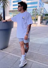 Remera blanca oversize de manga corta, con diseño gráfico de flor sonriente en el pecho.