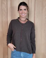 Sweater de tejido de punto en color marrón oscuro, con cuello redondo y mangas largas. Presenta un corte holgado y diseño minimalista.