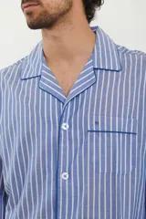 Pijama para hombre de camisa manga larga con botones y pantalón largo, ambos a rayas verticales celestes y blancas con ribetes azul marino.