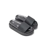 Sandalias tipo ojota color negro, con faja superior de textura geométrica, plataforma alta y suela estriada.