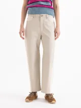 Pantalón de cuero color beige, de corte recto y holgado, con detalles de tejido texturizado en los laterales y bolsillos.