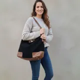 Bolso tipo hobo grande de eco cuero con textura símil gamuza color bordó, con refuerzos en la base y detalles en eco cuero marrón claro en las esquinas inferiores y tiras.