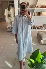 Vestido camisero midi celeste de lino, con cuello camisero, mangas 3/4 y bolsillos delanteros.