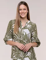 Vestido midi de silueta holgada en color blanco con estampado de hojas verdes. Presenta escote en V con cuello mao y botones frontales en la pechera, mangas tres cuartos abullonadas con puños elásticos y falda de corte evasé con niveles fruncidos.