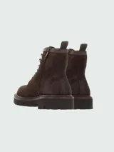 Botas acordonadas Boss modelo Julyo-Halb, confeccionadas en gamuza color marrón oscuro. Presentan un diseño robusto con suela de goma dentada, ganchos metálicos para los cordones y cuello acolchado en la parte superior.