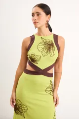 Vestido midi marrón con detalles en rojo, cuello redondo, diseño sin mangas, aberturas cut-out en la cintura y bordados artesanales de flores en contraste.