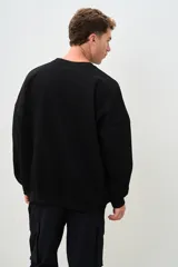 Buzo negro de corte amplio con cuello redondo y mangas largas.