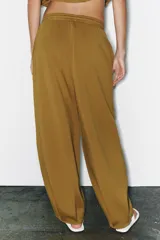 Pantalón de tiro medio y pierna ancha, confeccionado en hilatura con mezcla de algodón. Cuenta con cintura elástica con cordón de ajuste, bolsillos laterales ocultos y bajo abullonado con pliegues frontales.