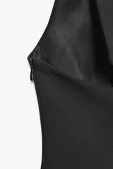 Top negro con cuello halter y escote en pico. Se ata con lazo en la espalda y tiene cierre lateral con cremallera oculta.