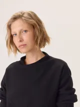 Buzo de lana color beige claro, con cuello chimenea y manga larga. Presenta trenzas de punto grueso en el frente y en los puños, con un diseño texturizado que se asemeja a espigas o ramas.