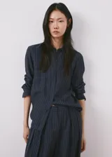 Camisa azul marino con diseño de rayas diplomáticas finas, cuello camisero clásico, mangas largas y cierre frontal con botones.