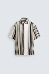 Camisa de manga corta con calce relaxed fit, confeccionada en tejido estructurado con algodón. Presenta un diseño de rayas verticales en tonos beige, negro y blanco, cuello solapa, cierre frontal con botones y aberturas laterales en el bajo.