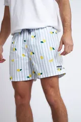 Short de baño con cintura elástica y cordón ajustable, confeccionado en tela ligera de secado rápido. Presenta un estampado botánico integral en tonos amarillos, blancos y azules, con dos bolsillos delanteros y uno posterior.