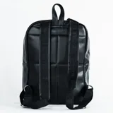 Mochila urbana negra de cuero sintético con diseño acolchado de hexágonos inspirado en un balón de fútbol. Cuenta con cierre principal, bolsillo frontal con cierre, correas ajustables y asa superior.
