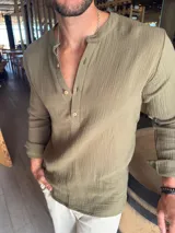 Camisa de manga larga confeccionada en muselina de algodón, con cuello mao y cierre frontal parcial de botones.