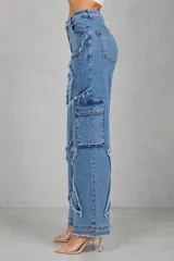 Jean de tiro medio con corte wide leg, confeccionado en denim azul. Presenta un diseño distintivo con apliques en forma de estrella con bordes deshilachados y bolsillos laterales tipo cargo.