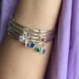 Set de tres pulseras rígidas plateadas con dije colgante de circonia azul.