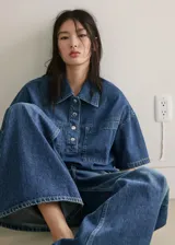 Jeans de denim azul de tiro medio y diseño wide leg largo, con cinco bolsillos, trabillas para cinto y cierre de botón y cremallera.