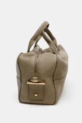 Bolso alargado tipo bowling color verde oliva, confeccionado en cuero con doble asa de mano y asa bandolera extraíble. Incluye bolsillo interior con cremallera y cierre principal con cremallera.