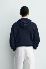 Jersey de punto con capucha, confeccionado en una mezcla de algodón y lana. Presenta un diseño de corte regular, manga larga y acabados en rib en puños y bajo.
