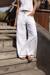 Pantalón blanco de lino con corte de piernas anchas, cadera al cuerpo y cintura media. Aplique de lino rayado en los costados en forma triangular.