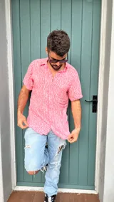 Camisa de fibrana color rosa con estampado de líneas verticales blancas, de manga corta y cuello clásico.