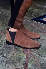 Bota corta de cuero color marrón con elástico negro en los laterales y suela negra.